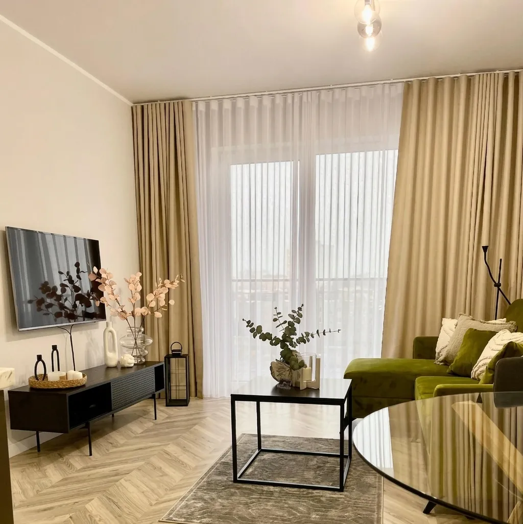 Salon z zieloną aksamitną sofą i zasłonami w odcieniu écru w Apartamencie Staroszkolna